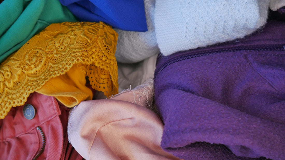 a pile of colorful clothing sitting on top of a bed