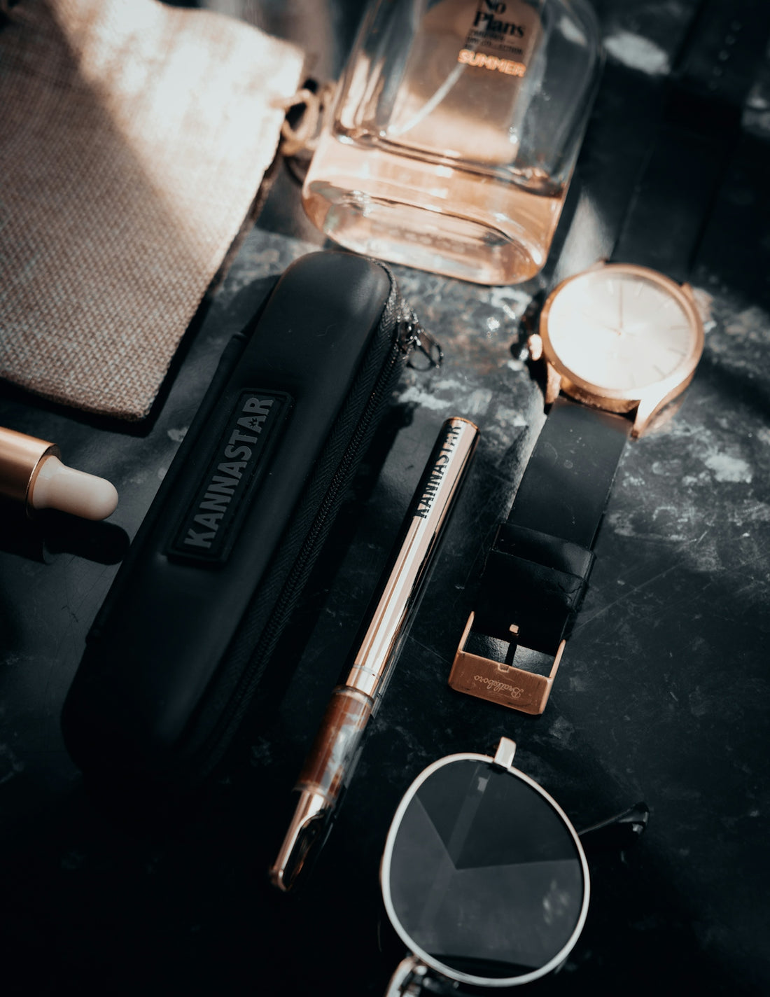 Flat lay of luxury accessories including watch and perfume