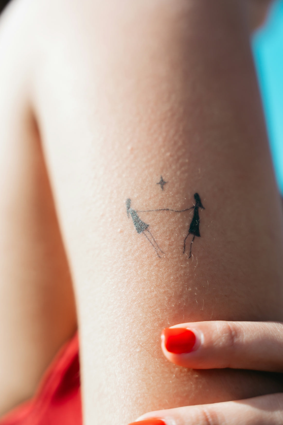 Minimalist tattoo of two figures holding hands on skin